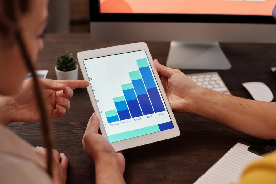 Mains tapant sur un ordinateur portable avec des graphiques de cryptomonnaies et l’écran d’un smartphone visible, en mettant l’accent sur la finance numérique.